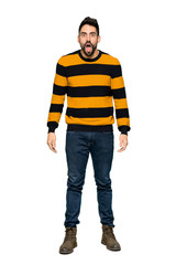Fototapeta premium Full-length shot of Handsome man with striped sweater with surprise and shocked facial expression on isolated white background