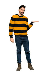 Full-length shot of Handsome man with striped sweater presenting an idea while looking smiling towards on isolated white background