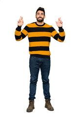 Full-length shot of Handsome man with striped sweater with fingers crossing and wishing the best on isolated white background