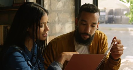 Front view of happy young Asian couple discussing over menu card in cafe 4k - Powered by Adobe