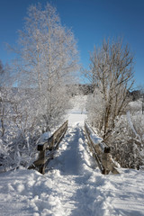 Snow covered footbridge on a sunny winter day