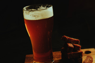 Glass of beer and croutons on a black background