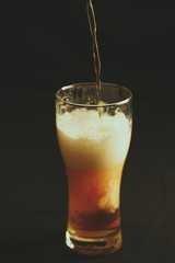 A glass of beer on a black background pour a intoxicating drink, close-up