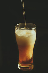 A glass of beer on a black background pour a intoxicating drink, close-up