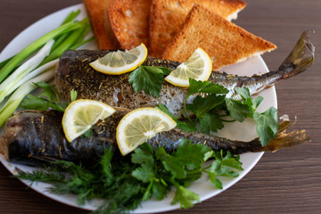 baked fish under lemon on dish with onion herbs and toast
