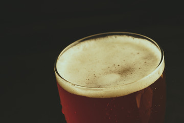 A glass of beer on a black background, close-up