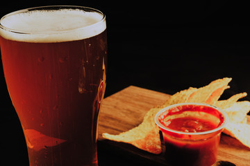 Glass of beer and croutons on a black background