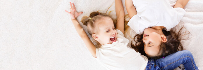 Happy little sisters lying on back top view