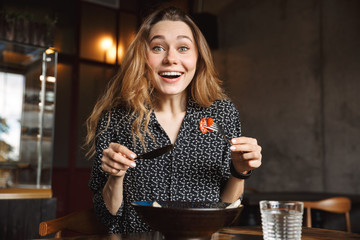 Excited beautiful young pretty woman sitting in cafe indoors have a breakfast.