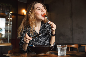 Excited beautiful young pretty woman sitting in cafe indoors have a breakfast.