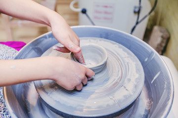 Fototapeta premium Child hands working with clay on pottery wheel