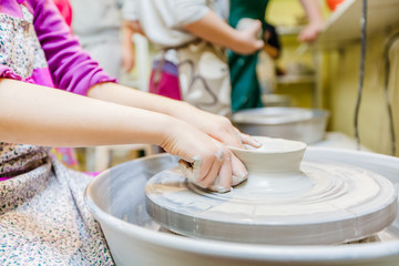 Child hands shaping clay at wheel