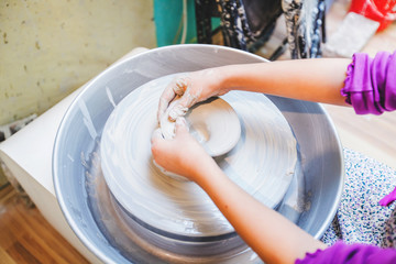 Child hands shaping clay at wheel