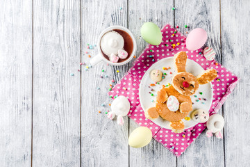 Funny easter breakfast food, kids pancake in form of bunny rabbit, with hot chocolate, top view wooden background copy space