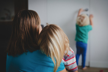 problems in family - tired mother comforting crying daughter while other child is hurt