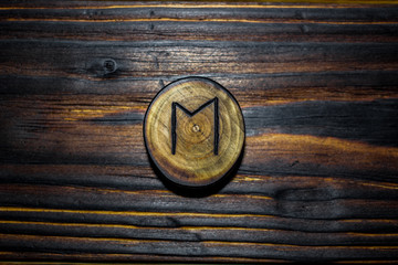 Rune Ehwaz carved from wood on a wooden background - Elder Futhark