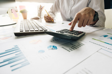 Close up of businessman or accountant hand holding pen working on calculator to calculate business...
