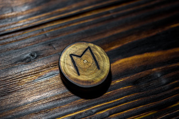 Rune Ehwaz carved from wood on a wooden background - Elder Futhark