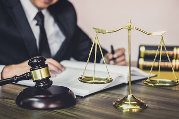 Judge gavel with Justice lawyers, Gavel on wooden table and Counselor or Male lawyer working on a documents at law firm in office. Legal law, advice and justice concept