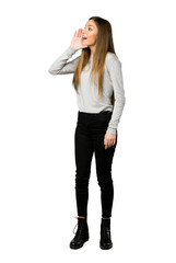 Fototapeta premium Full-length shot of young girl shouting with mouth wide open to the lateral on isolated white background
