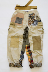 Sand colored vintage pants with patchwork decor details, on a white background.