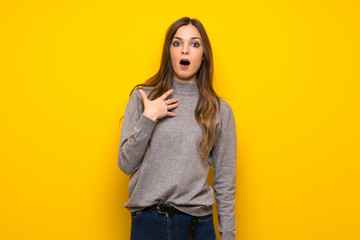 Young woman over yellow wall surprised and shocked while looking right