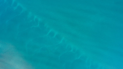 Fototapeta na wymiar Sand, rock, and sea patterns on cristal clear waters.