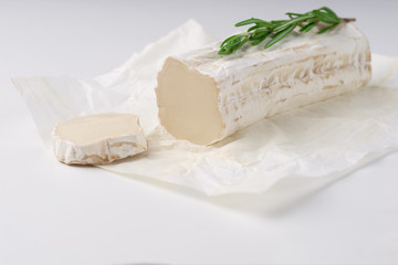 Stick of a goat cheese on paper on  the white background.