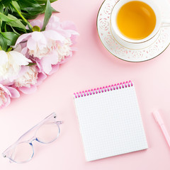 Beautiful cosmetics and flowers flat lay with note book, herbal tea on pastel background.