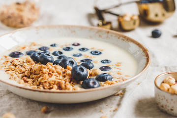 Healthy breakfast, a bowl with organic granola, chocolate pieces, fresh blueberries, hazelnuts and soya milk.