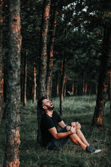 Young depressed man sitting alone in the forest