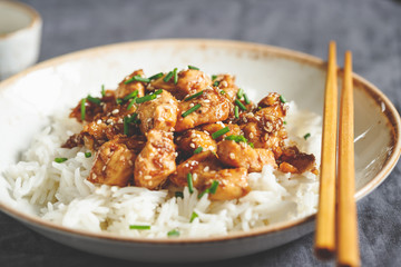 Sesame chicken pieces with rice on a ceramic plate. Chinese traditional dish.