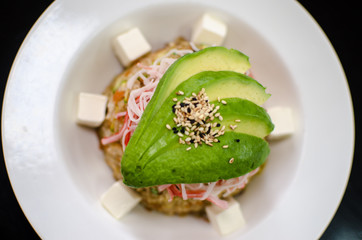 Yakimeshi fried rice with avocado and surimi presented in white plate against a dark backgound.