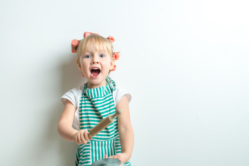 toddler in role of crasy andgry housewife with frying pan and pink curlers