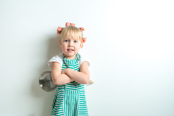 toddler in role of crasy andgry housewife with frying pan and pink curlers