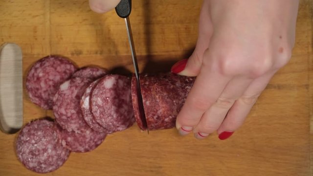 Slicing sausage on a cutting board. Beef sausage. Cut with a kitchen knife.