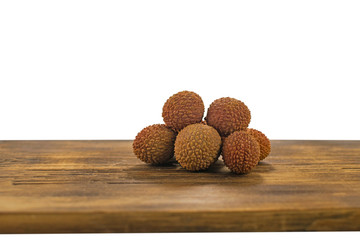 Fresh lychee and peeled showing the red skin and white flesh with green leaf on a wooden background. Lychi with leaves - tropical fruit.