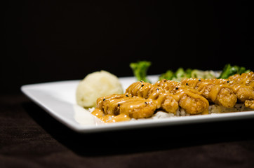 Japanese pan fry with salad and rice in black background.