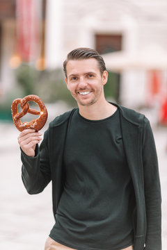 Beautiful Young Man Holding Pretzel And Relaxing In Park