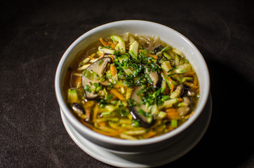 Shiitake soup in white bowl in black background