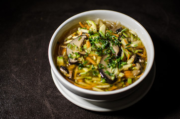 Shiitake soup in white bowl in black background