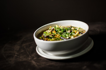 Shiitake soup in white bowl in black background