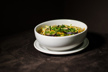 Shiitake soup in white bowl in black background