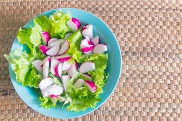 Bright salad. Radish and greens in blue plate