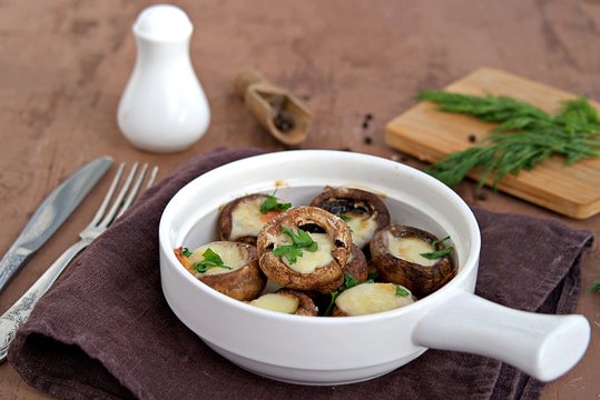 Hot appetizer, baked mushrooms with suluguni cheese in white ceramic form. Georgian cuisine.