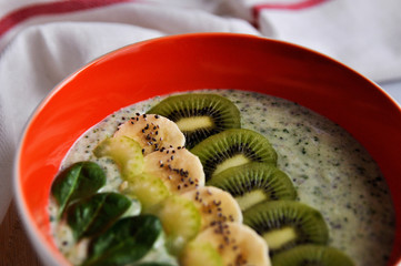 Bright plate with a healthy Breakfast power bowl made of natural yogurt, Chia seeds, banana, kiwi, celery and spinach on a gray background. top view. copyspace