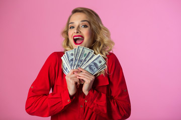 beautiful young girl in a red shirt with dollars in their hands on a pink background