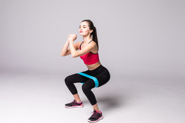 Athletic girl working with resistance band. Portrait of attractive girl with beautiful athletic body isolated on white background. Strength and motivation