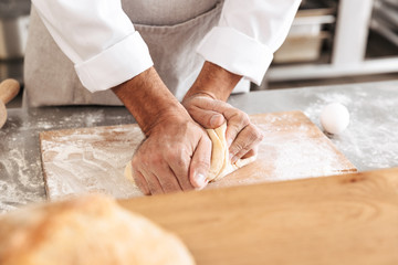 Closeup portrait of male hands mixing dough for pastry, on table at bakery or kitchen