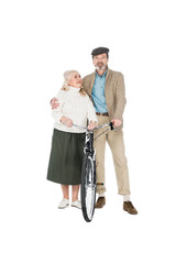 cheerful pensioner hugging happy wife while holding bicycle isolated on white